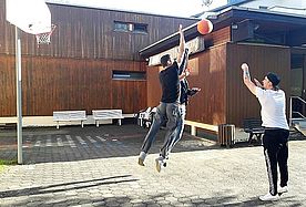 Das Bild zeigt drei männliche Jugendliche beim Basketballspiel